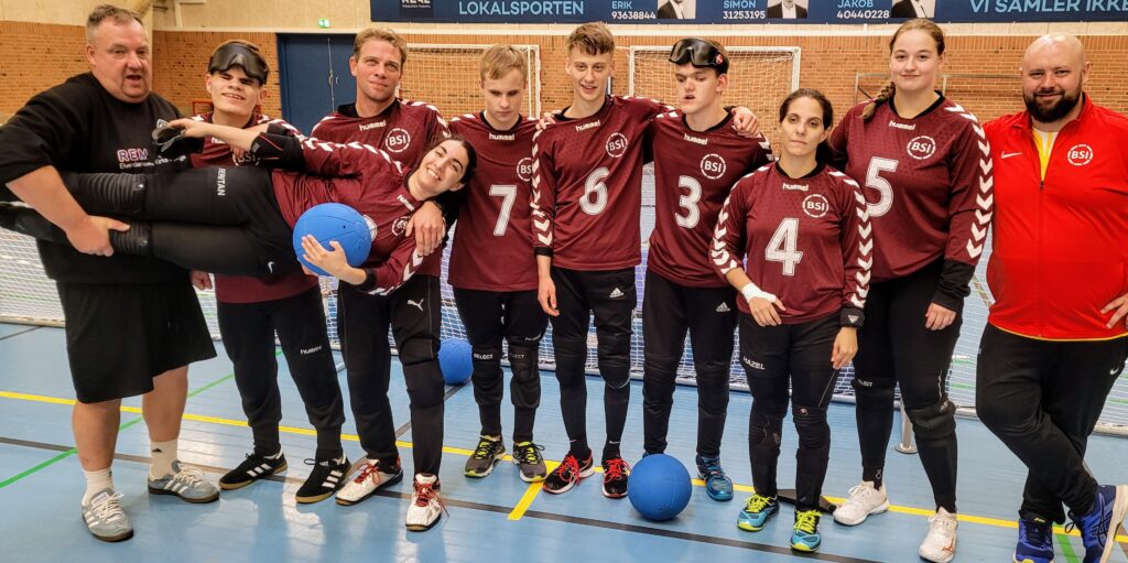 Gruppebillede af 10 mennesker i rødt tøj og med bolde.
