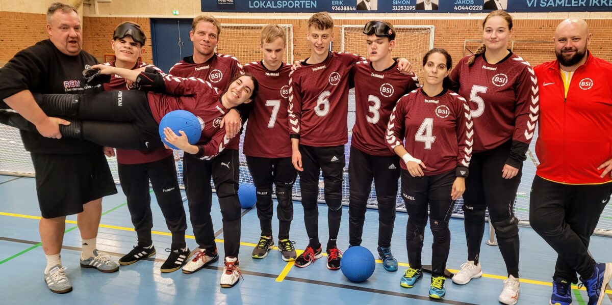 Gruppebillede af 10 mennesker i rødt tøj og med bolde.